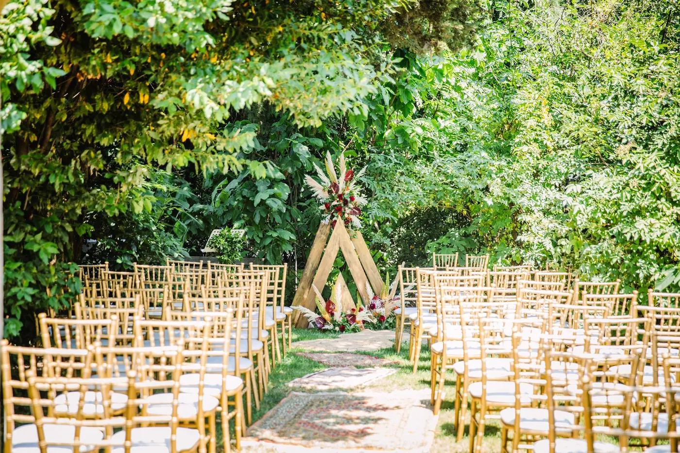 Cérémonie de mariage extérieure avec arche végétale et assises pour les invités.