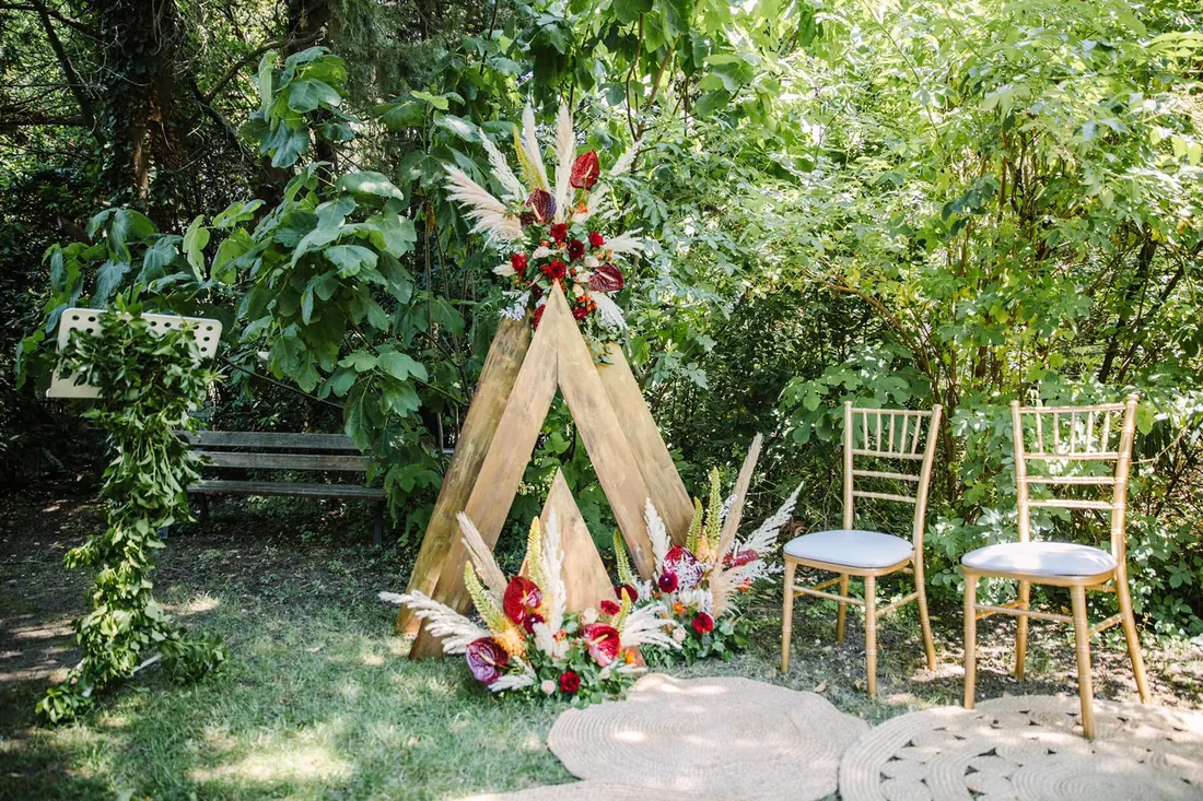 Décor de cérémonie de mariage dans un jardin avec assises blanches et compositions végétales.