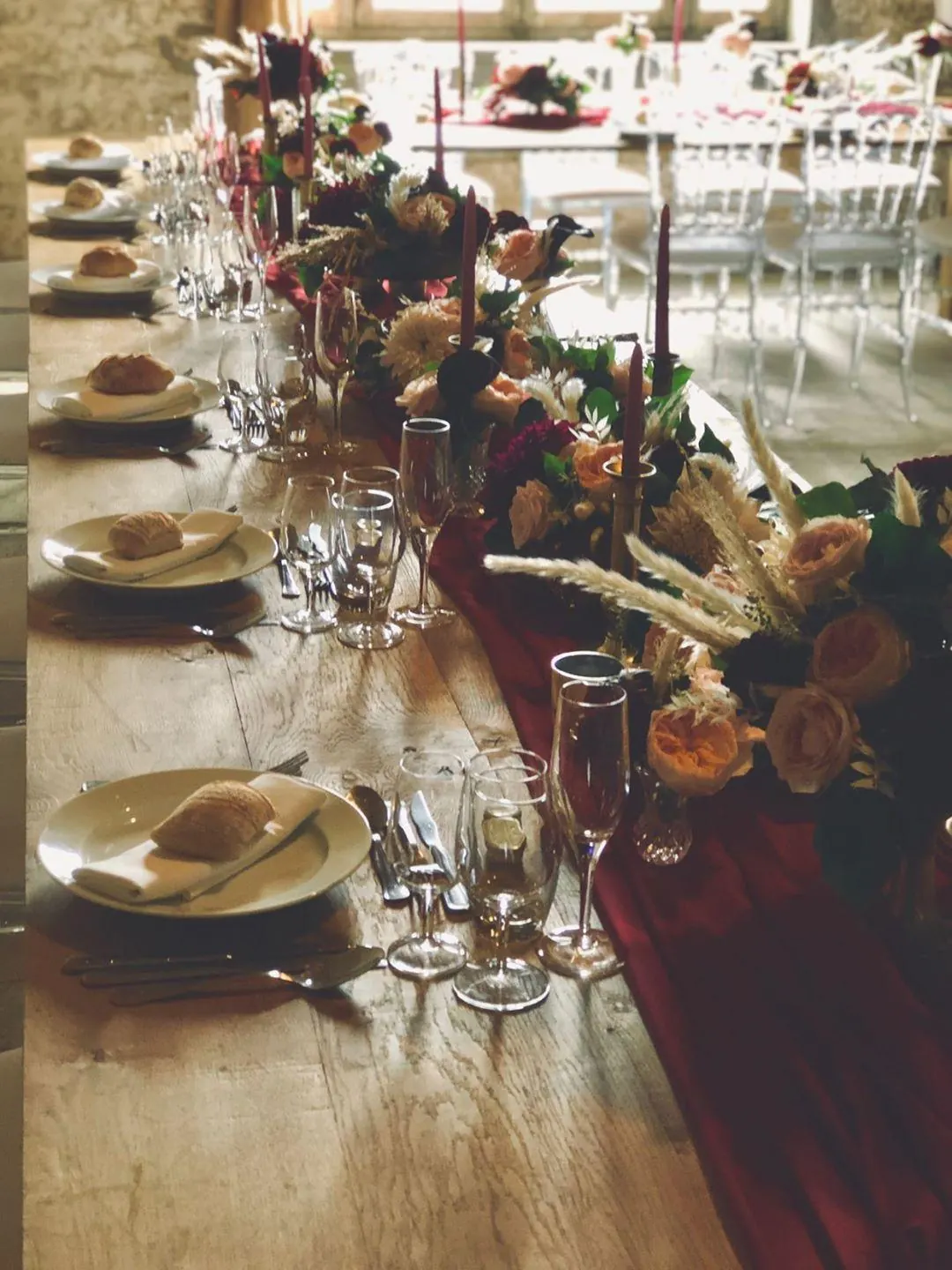 Longue table de banquet dressée pour une réception de mariage champêtre chic.