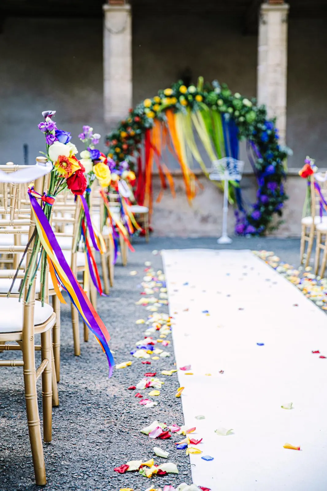 Allée de cérémonie extérieure décorée avec rubans blancs et compositions florales.